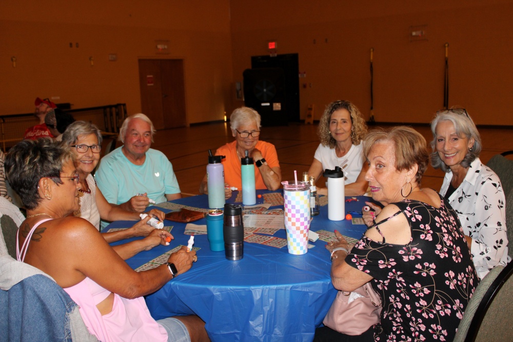 Same group of players sit closer to the camera, marking bingo cards and chatting